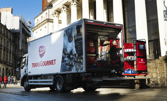 Un chauffeur-livreur avec un roll sur le hayon d'un camion Transgourmet