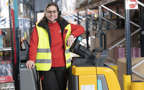 Une préparatrice Transgourmet sur un chariot en entrepôt