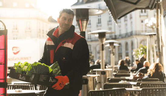Patrice, chauffeur-livreur chez Transgourmet portant une cagette de fruits et légumes