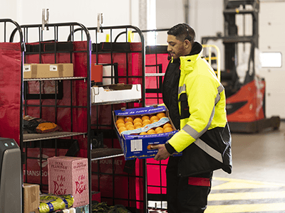 Un préparateur charge des produits sur un roll en entrepôt