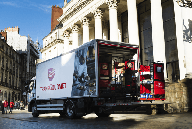Un chauffeur-livreur avec un roll sur le hayon d'un camion Transgourmet